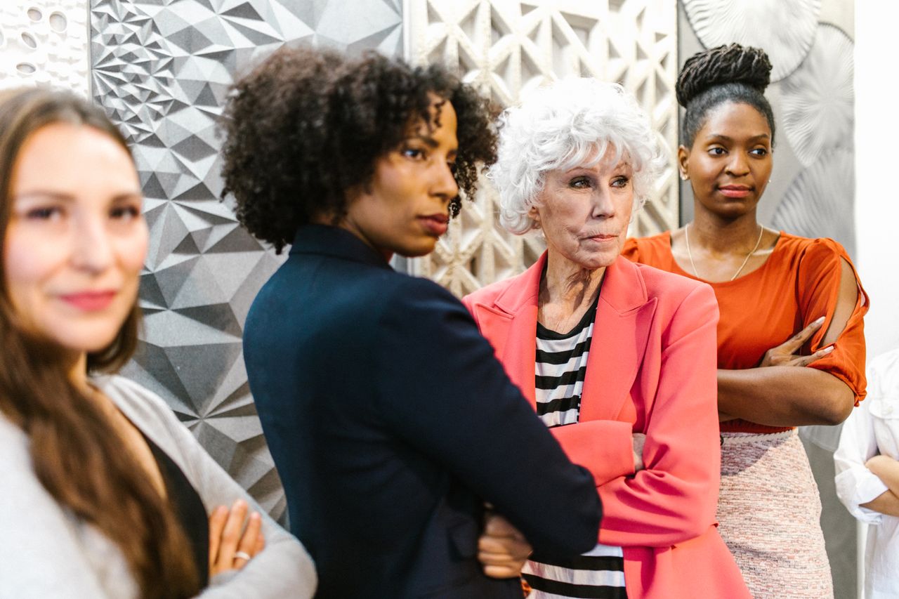 A diverse group of women standing confidently in an office environment, showcasing empowerment and leadership.